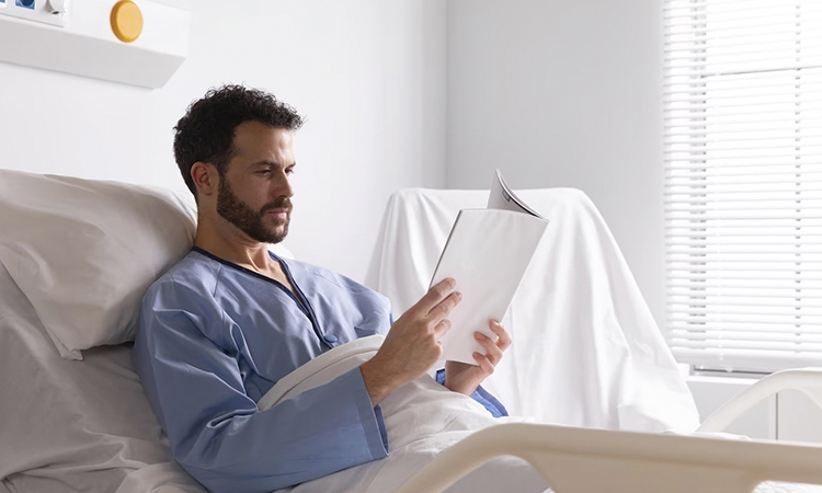 Мужчина читает книгу в больничкой койке